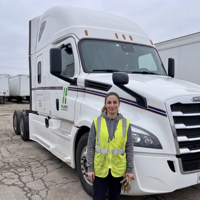 Truck driver standing with a Halimeh Transportation Inc truck