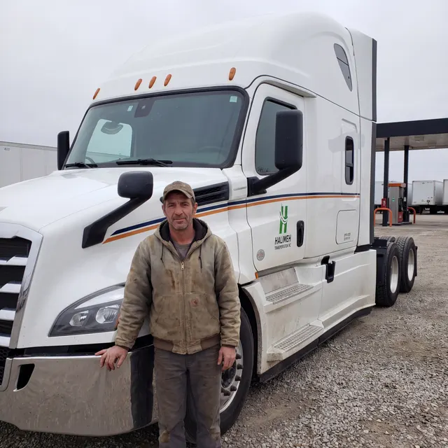 Truck driver standing with a Halimeh Transportation Inc truck